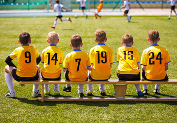 Young Football Players. Young Soccer Team Sitting on Wooden Bench. Soccer Match For Children. Young Boys Playing Tournament Soccer Match. Youth Soccer Club Footballers © matimix