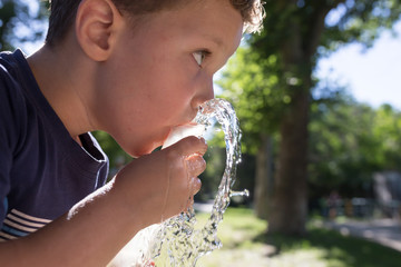 boy drinking water outdoors
