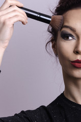 Obraz premium Beautiful young girl holding a makeup brush and blending face