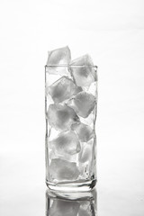 Glass with ice cubes on white background