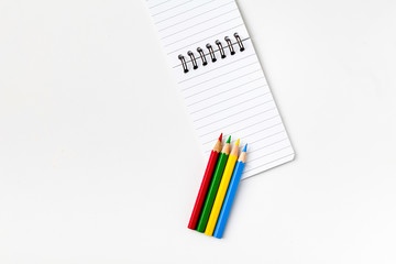 Note book with color pencils on white background 