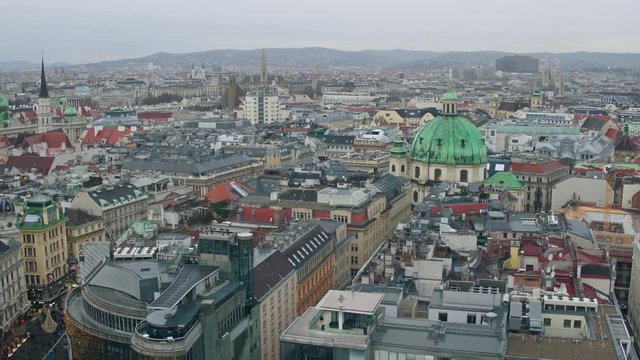 Old low-rise and modern buildings' roofs in Vienna on a cloudy day, Austria. 4K overview pan shot