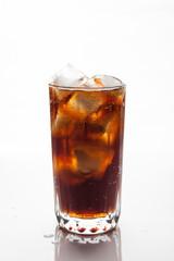 Cola with ice in a glass on white background