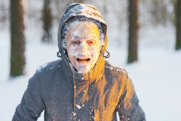 Fototapeta na wymiar Portrait of an young frozen man with an open mouth while Jogging in a Blizzard in the woods. Face covered with snow.