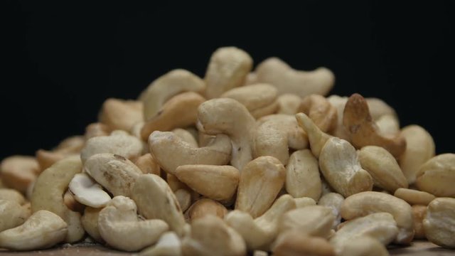Pile of cashew nuts on a wooden table isolated on black, rotating 