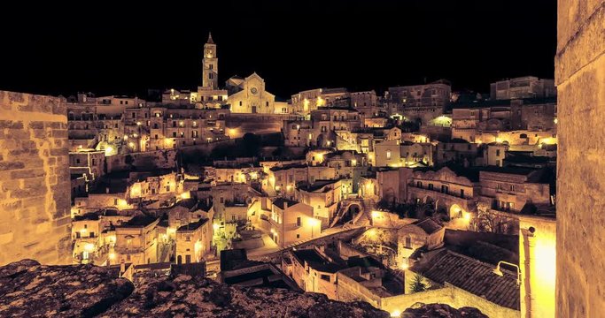 panoramic view of typical stones (Sassi di Matera) and church of Matera at night, with golden abstract blinking sparkle celebration fireworks light, happy new year holiday