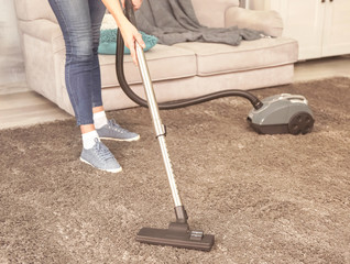 Cleaner hoovering carpet in room