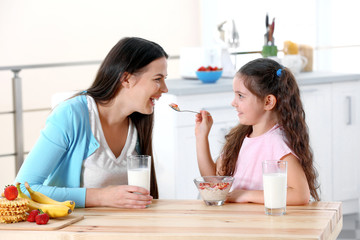 Mother and daughter having healthy breakfast in kitchen
