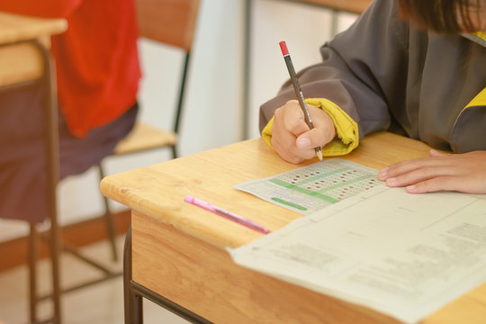 Students hand holding pencil writing doing examination, backgrou