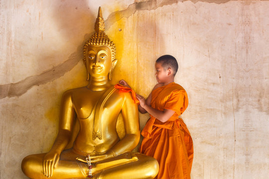 Young novices monk scrubbing buddha statue at temple in thailand