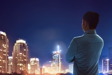 man standing looking city at night