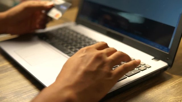 A man paying for online shopping using laptop and credit card. This image is illustrated the online payment concept via internet. Slightly warm tone filter.