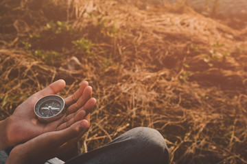 Hand with compass at mountain road at sunset sky 