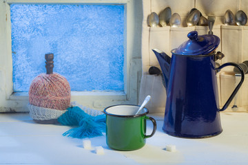 Aromatic cup and coffee pot with spoons by frozen window
