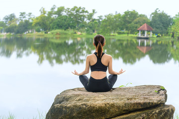 Fototapeta na wymiar Asian Young woman doing yoga in morning park, Asian woman is practicing yoga at mountain lake