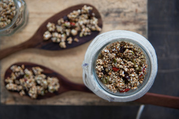 Healthy vegetariam sweet breakfast concept. Overhead still life of granola in glass jar on dark shabby background.