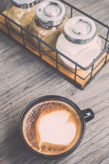 Hot latte coffee in black cup on grey wooden table background. V