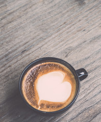 Hot latte coffee in black cup on grey wooden table background. V