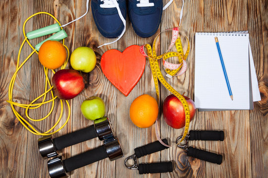 Heart, apples and oranges, diet, healthy , dumbbells  a jump rope on  wooden background