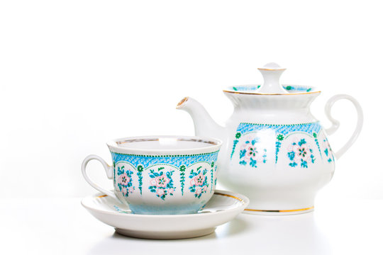 Vintage ornamental tea set, cup with saucer and kettle. Porcelain dishes. Decorative wallpaper