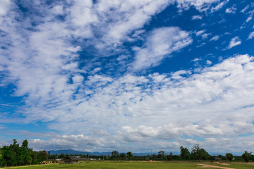 blue sky with clouds with grass field and distant mountains