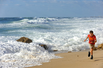 Boy runs along the shore of the Mediterranean Sea in Israel