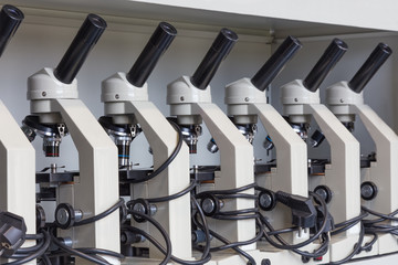 Cabinet with row of microscopes on shelve at biology