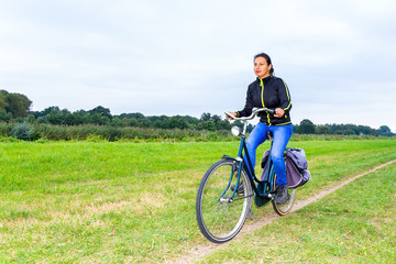 Obraz premium Colombian woman cycling on path in dutch nature landscape