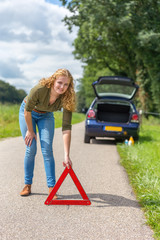 Dutch woman placing hazard warning triangle on rural road