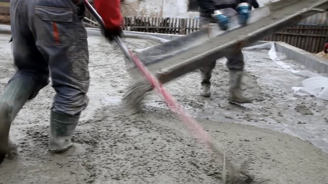 Pouring concrete mix from cement mixer on concreting formwork