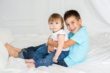 Children. Brother and sister hug in the parents bed