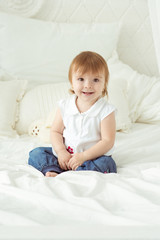 Cute smiling little girl sitting in the parents bed