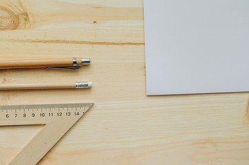 White paper, pencil, pen, triangle on the wood desk in daylight