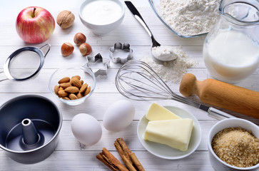Baking ingredients: flour, eggs, milk, butter, brown sugar, cinnamon, almonds, nuts, yogurt, walnut and apple with eggbeater, cake pans, rolling pin and strainer