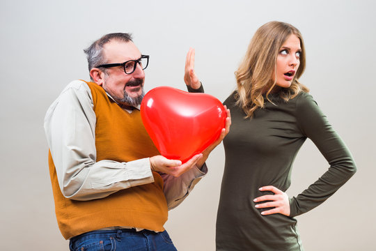Nerdy man wants to give heart shape balloon to a beautiful woman to show her his love,but she is not interested.
