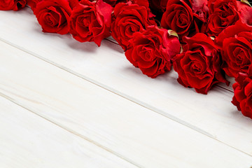 Buds of red roses on white wooden background