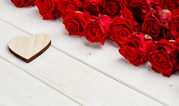 Buds of red roses on white wooden background