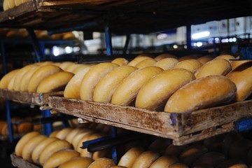 many loaves of fresh bread on a shelf in a bakery