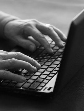 old woman typing on a laptop
