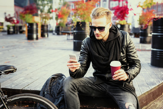 Hipster man having morning coffee and using mobile phone