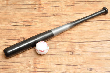 A baseball bat and ball isolated on a wooden background