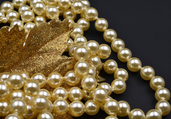 Pearls and glittering golden leaf with black background.