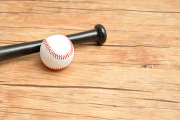 A baseball bat and ball isolated on a wooden background