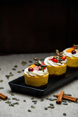 Delicious pumpkin cupcakes on black dish.