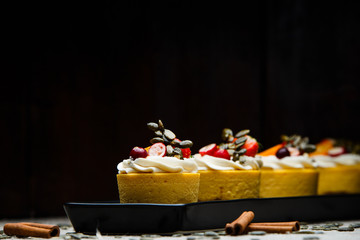 Delicious pumpkin cupcakes on black dish.