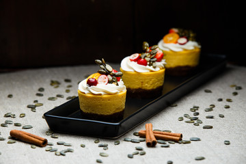 Delicious pumpkin cupcakes on black dish.
