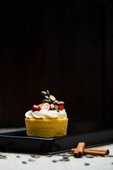 Delicious pumpkin cupcakes on black dish.