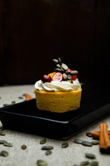 Delicious pumpkin cupcakes on black dish.