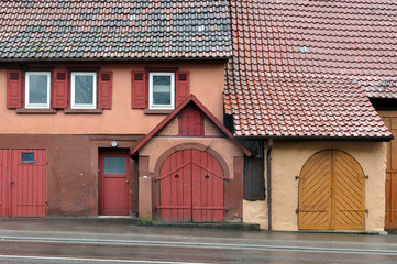 Facade of an old building with the entrance gate red and orange and a pitched tiled roof. Waiblingen, Baden-Wurttemberg, Germany.