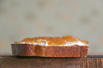Sandwich of bread, cream cheese and pike caviar closeup. Side view, empty place.
